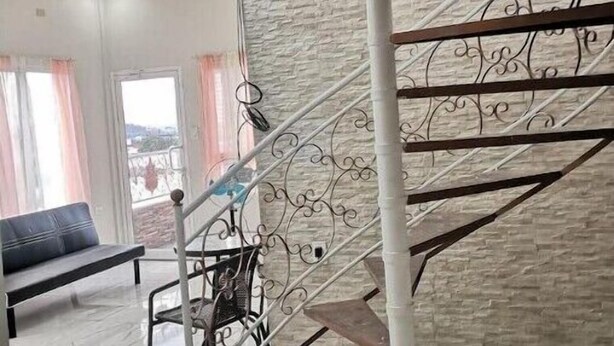 Un intérieur moderne avec un escalier en colimaçon, un mur d’accent en pierre et une vue dégagée grâce à de grandes fenêtres.