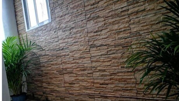 Ein Zimmer mit einer Steinwand, einem Fenster und einer Steinsitzbank.