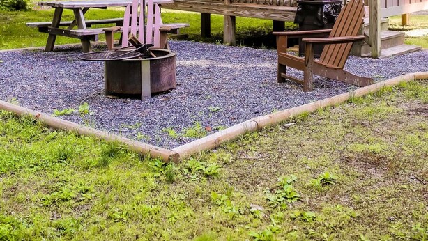 Un chalet rustique doté d’une terrasse en bois, d’un foyer extérieur et de meubles de jardin.