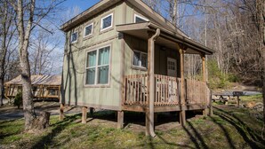 Une cabane en bois dotée d’un balcon, entourée d’arbres.