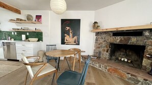 A modern kitchen with a stone fireplace, wooden dining table, and chairs. - Joshua Tree- Hot tub, Walk to food & shops, a few minutes from JTNP (Joshua Tree)