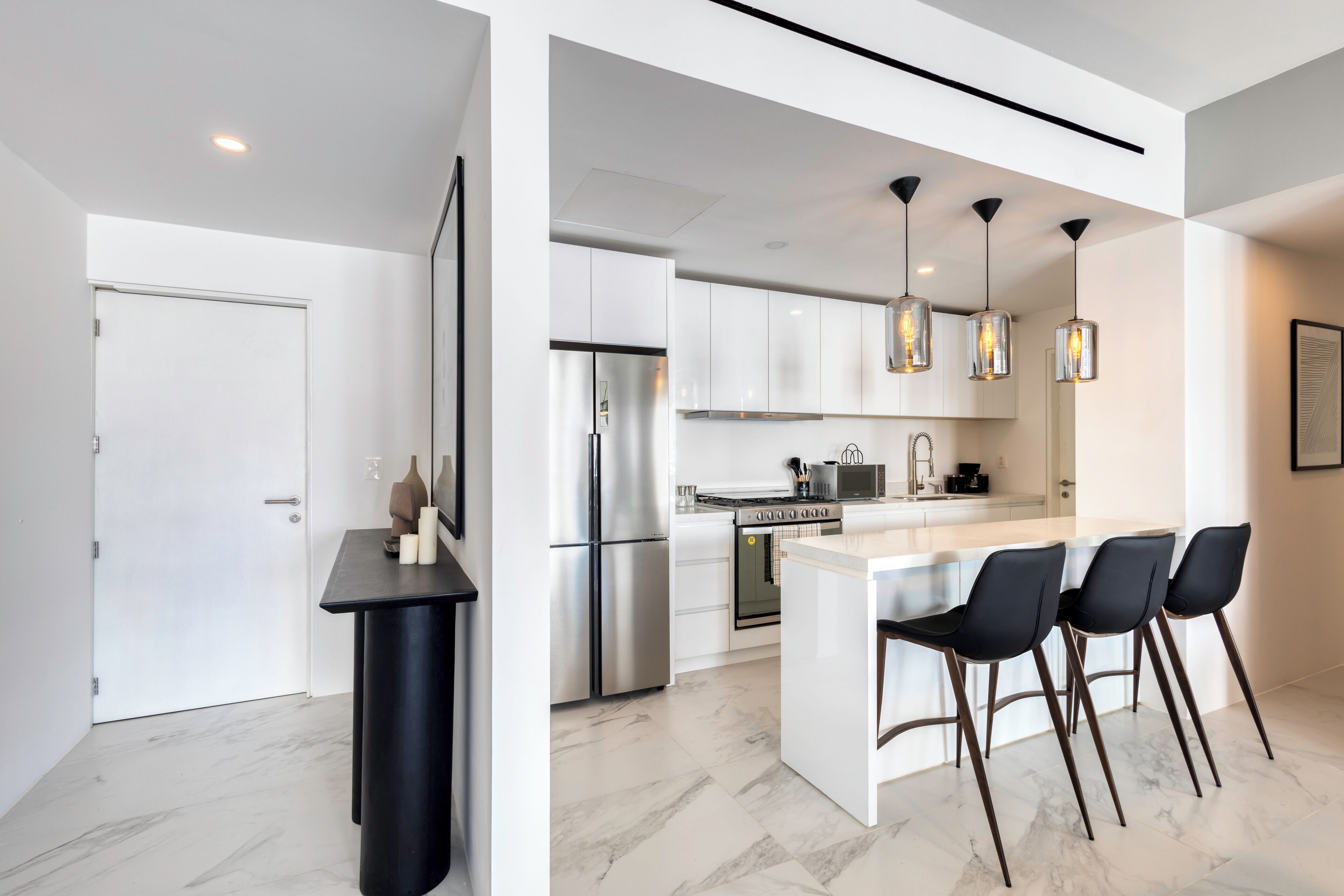 A modern kitchen with a central island, stainless steel appliances, and pendant lighting.