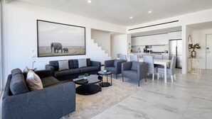 A modern living room with a sofa set, coffee table, and a painting of elephants.