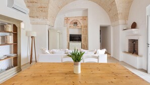 Amplia sala de estar con una mesa de comedor de madera, sofás blancos y un gran techo de ladrillo abovedado.
