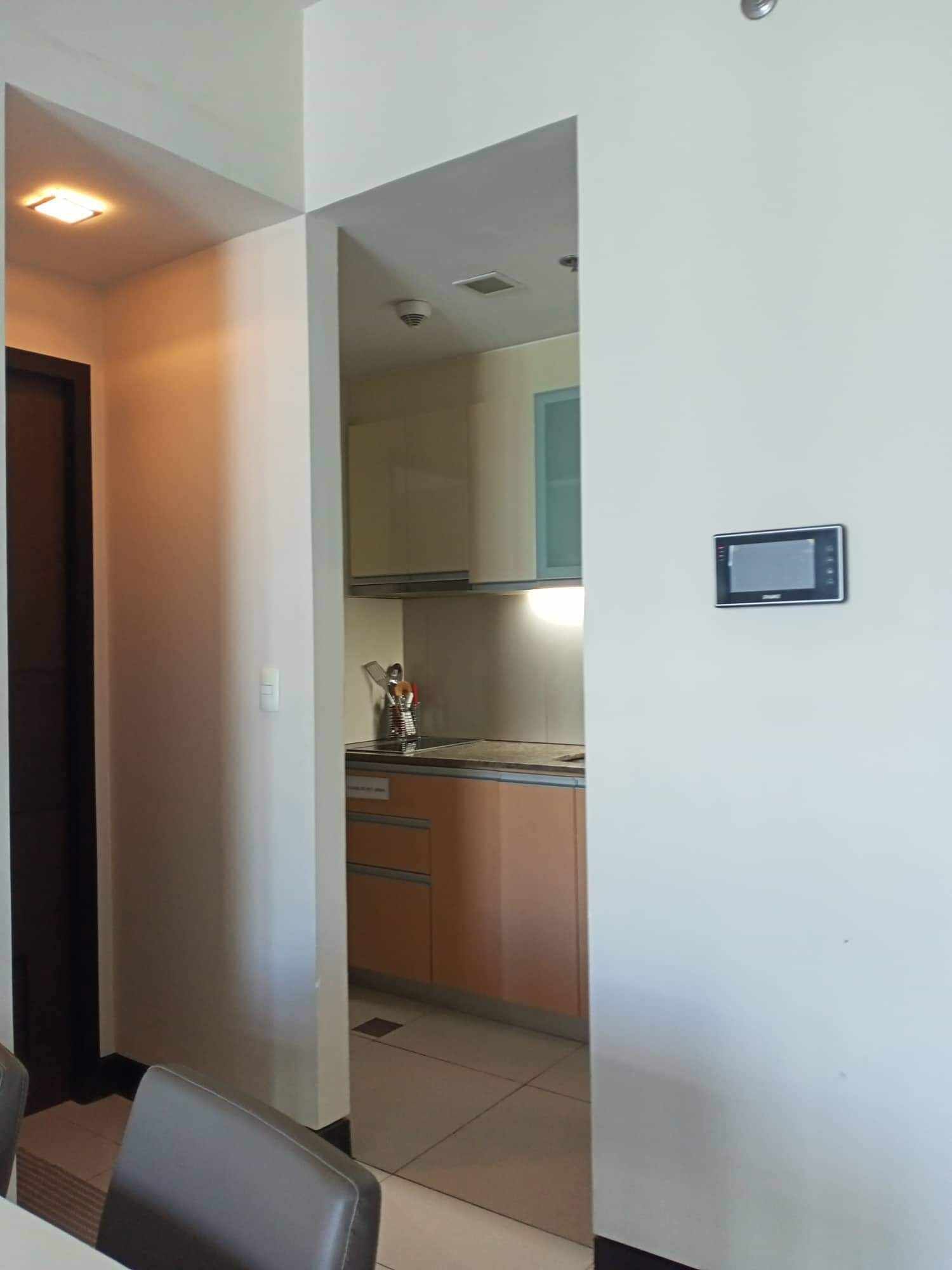 Un couloir étroit mène à une cuisine équipée de placards, d’une cuisinière et d’un petit écran fixé au mur.