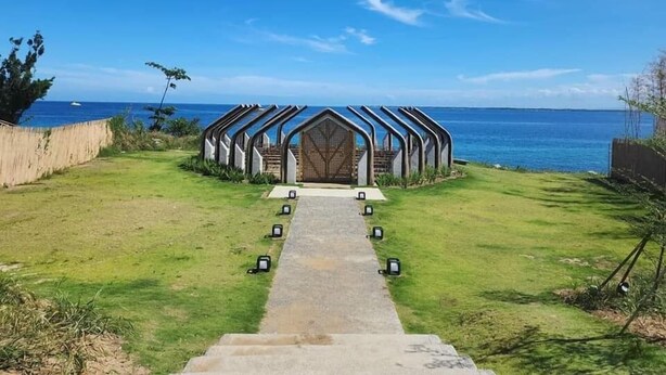 A pathway leading to a structure with a unique architectural design, situated by a body of water. - ROOM for RENT in Mactan Newtown (Lapu-Lapu)