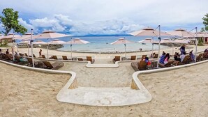 A beachside resort with sun loungers and umbrellas, a sandy beach, and a view of the ocean. - ROOM for RENT in Mactan Newtown (Lapu-Lapu)