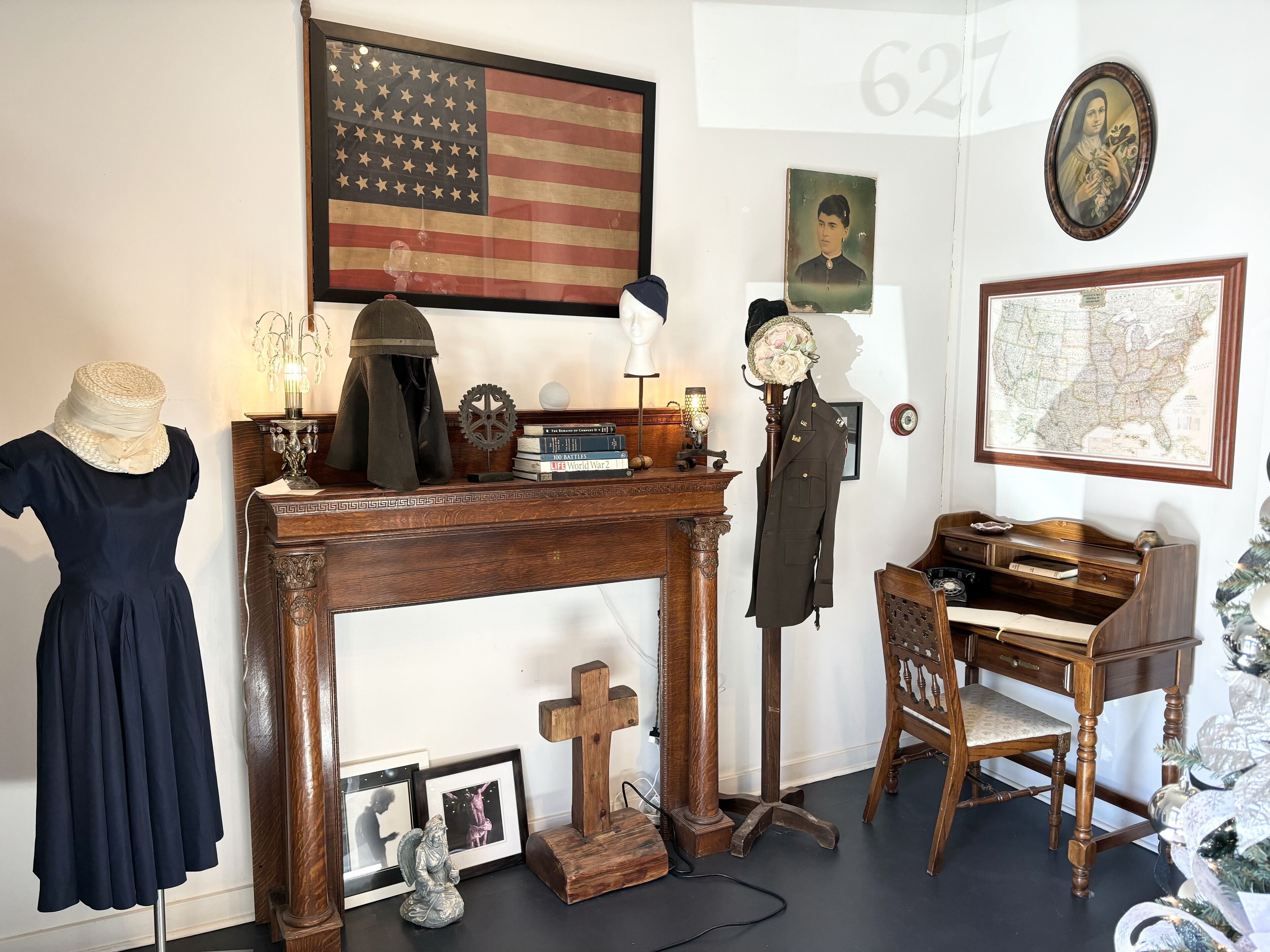 Ein Zimmer mit Schreibtisch aus Holz, einer in ein Kleid gehüllten Mannequins, einem Kamin, einer Karte und einem Porträt an der Wand.