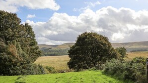 A grassy field with trees and a fence. - The Shearer's Hut (Holmfirth)