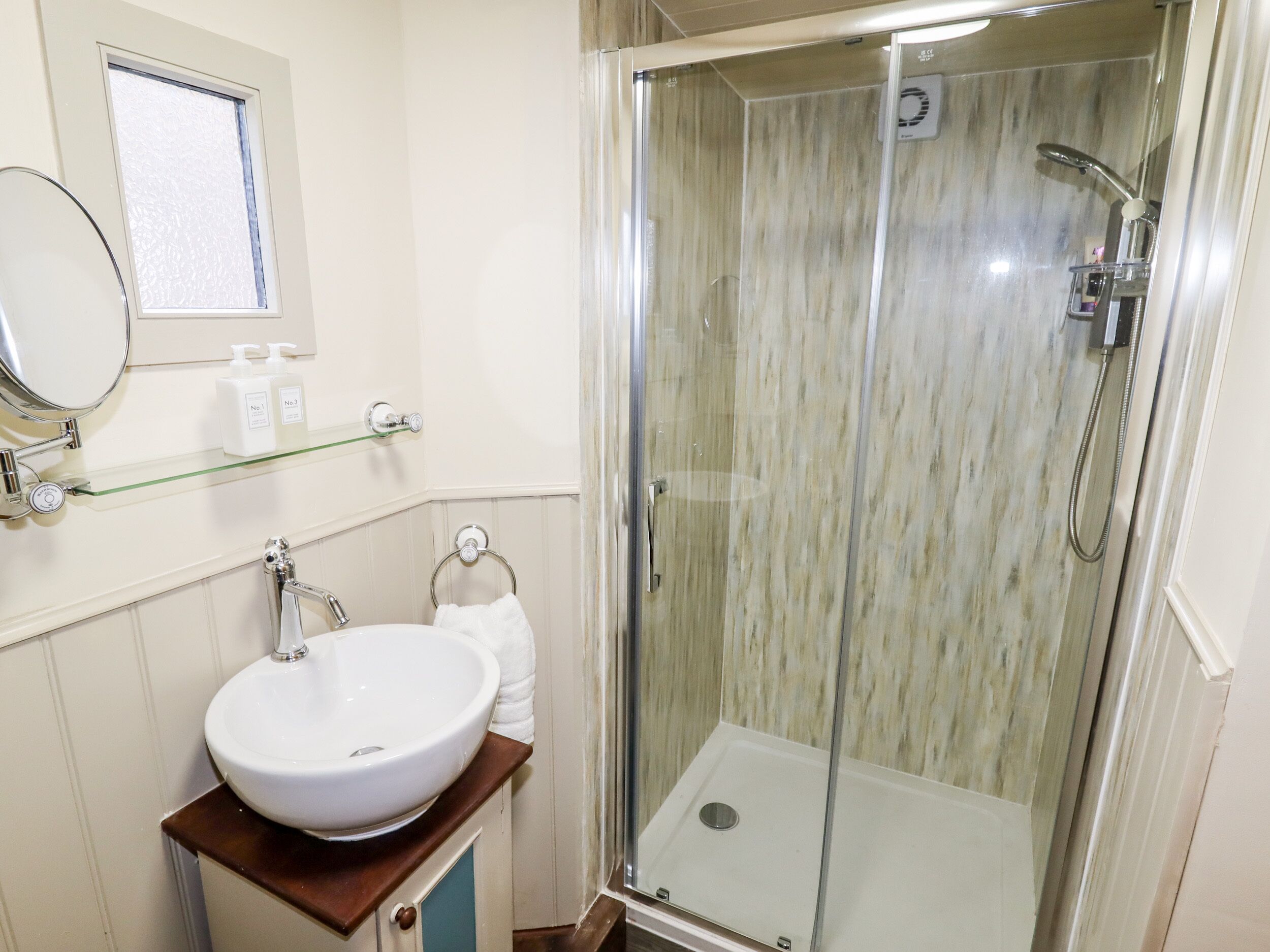 Un baño con ducha de vidrio, un lavabo blanco y un espejo.