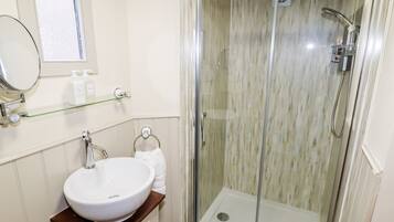 Un baño con ducha de vidrio, un lavabo blanco y un espejo.