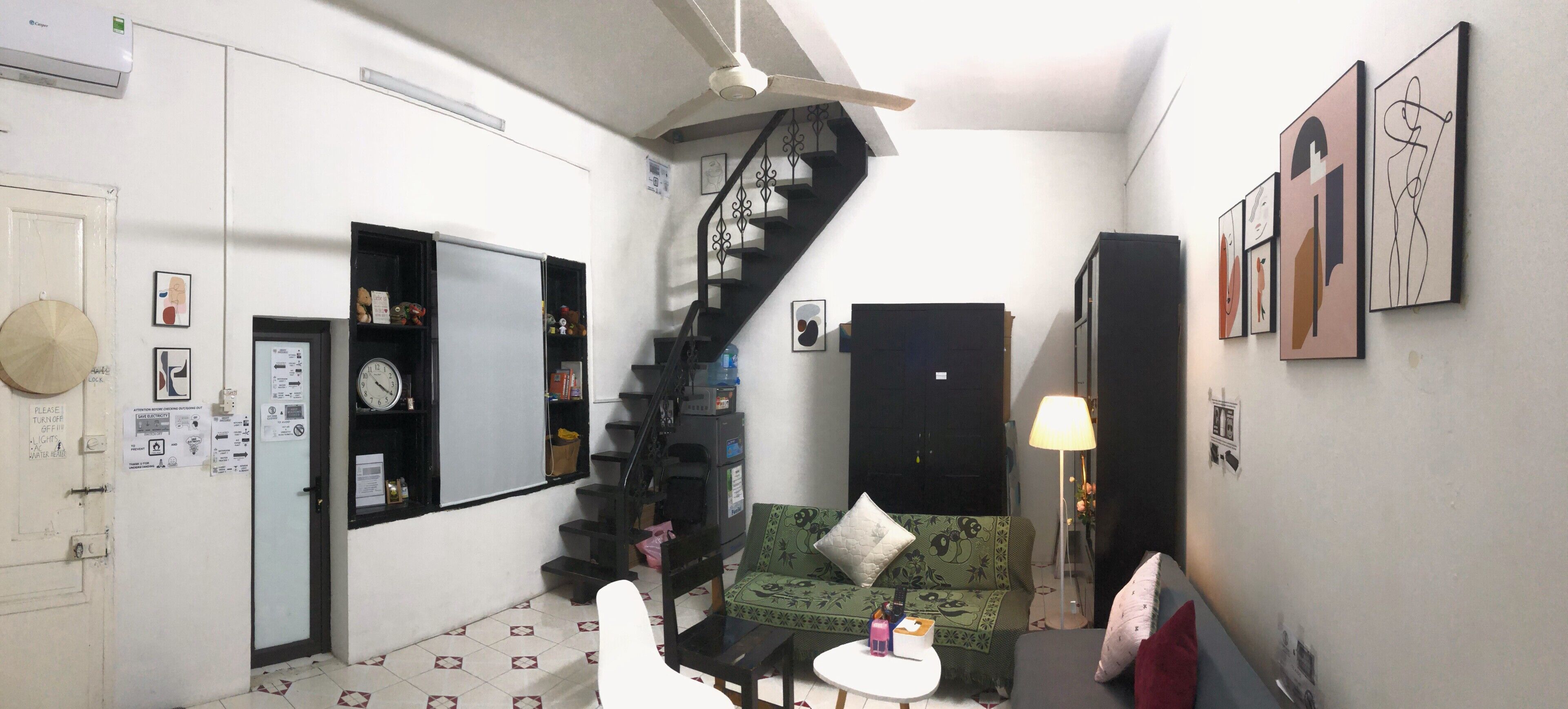 A compact living space with a staircase, a sofa, a small table, and wall art.