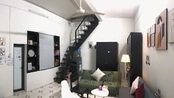 A compact living space with a staircase, a sofa, a small table, and wall art.