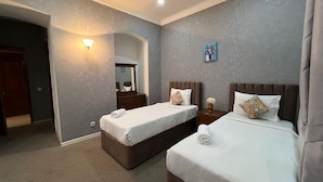 A hotel room with two beds, a nightstand, a lamp, and a painting on the wall. - Swan Hotel Baku  (Baku)