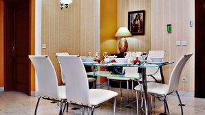 A dining area with a glass table, white chairs, and a lamp. - Swan Hotel Baku  (Baku)