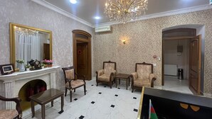A formal room with a fireplace, two armchairs, a table, and a chandelier. - Swan Hotel Baku  (Baku)