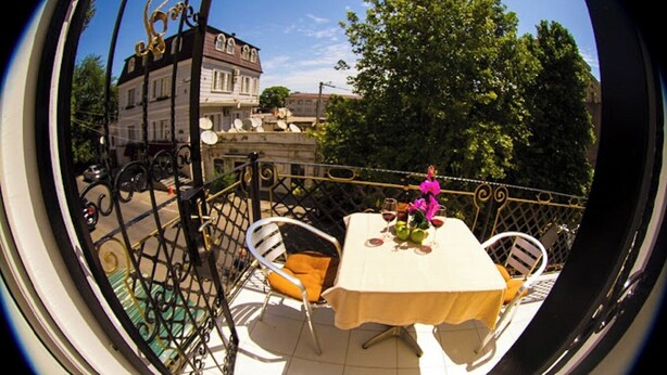 A dining area with a table set for two, outdoor seating, and a view of a building with satellite dishes. - Swan Hotel Baku  (Baku)