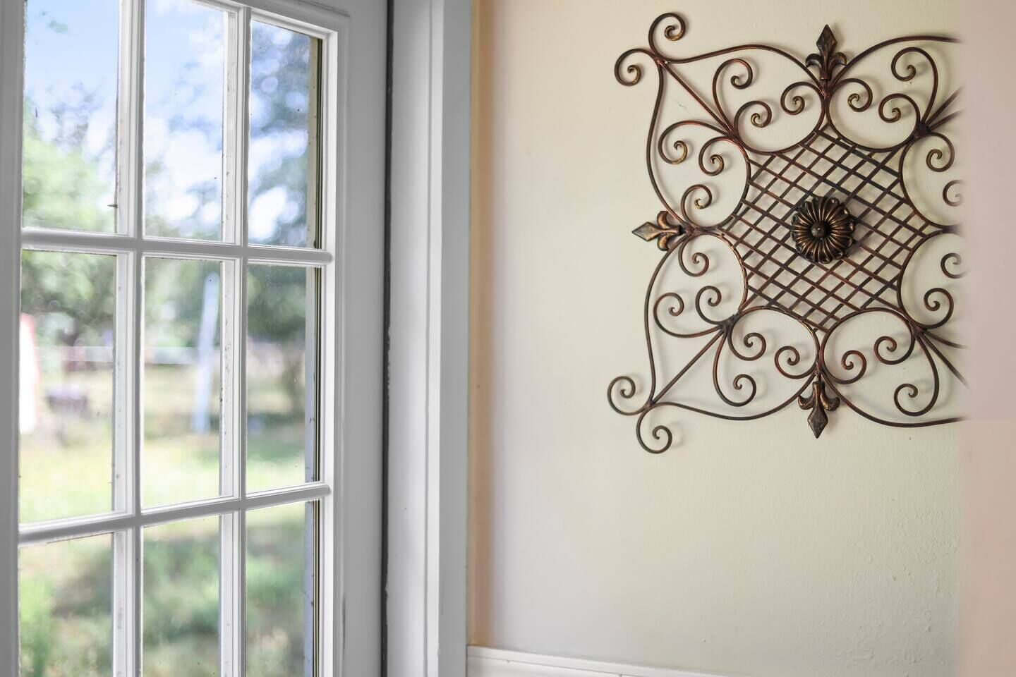 A room with a large window and a decorative metal wall hanging.