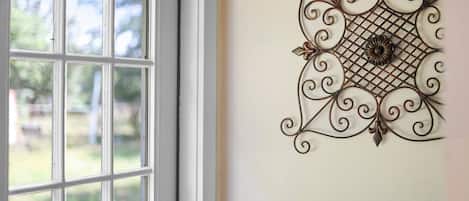 A room with a large window and a decorative metal wall hanging.