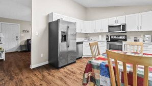 A modern kitchen with white cabinets, stainless steel appliances, and a wooden dining table. - Riverview beatiful acre home Pet/RV/boat Friendly (Riverview)