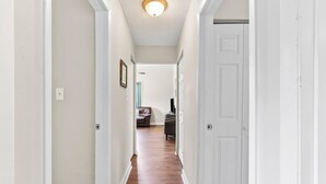 A hallway with white walls and wooden flooring leading to a room with a brown leather sofa and a TV. - Riverview beatiful acre home Pet/RV/boat Friendly (Riverview)