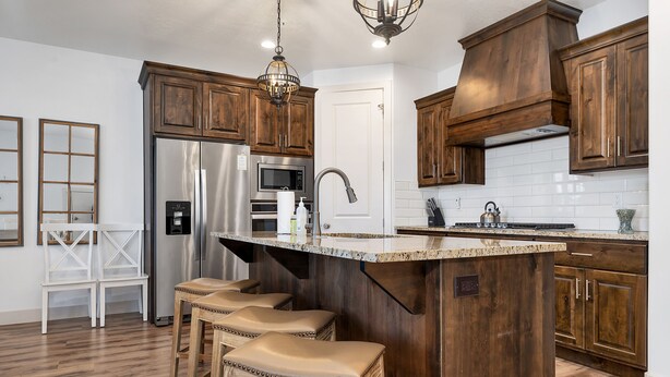 Una cocina con armarios de madera, un refrigerador de acero inoxidable, un microondas y una isla grande con taburetes.