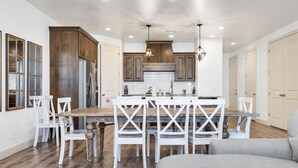 Una cocina amplia con armarios de madera, una isla central y sillas blancas.
