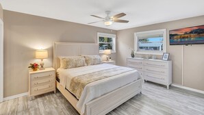 A bedroom with a bed, nightstands, a dresser, a ceiling fan, and a TV on the wall. - Private Home with Beautiful Backyard & Pool Close to Beach in Palm Beach Gardens (West Palm Beach)
