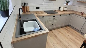 Cocina moderna con una isla central, un lavamanos integrado y una campana extractora negra.