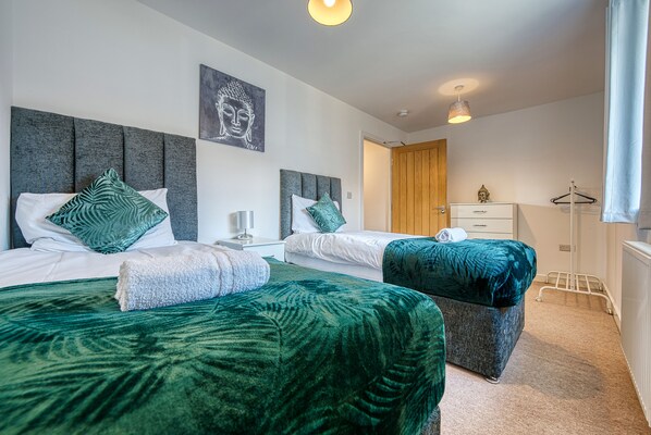 Two large beds with matching bedding and headboards, accompanied by bedside tables and lamps.