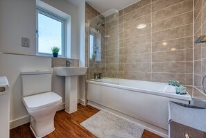 Enjoy a refreshing soak in the spacious bathtub and glass-enclosed shower area.