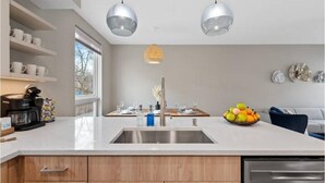 Une cuisine moderne dotée d’un grand îlot central, d’appareils électroménagers en acier inoxydable et d’un panier à fruits.
