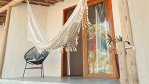 A hammock chair under a wooden pergola, a wooden door, and a small potted plant. - Vila dos Lobatos (Porto Seguro)