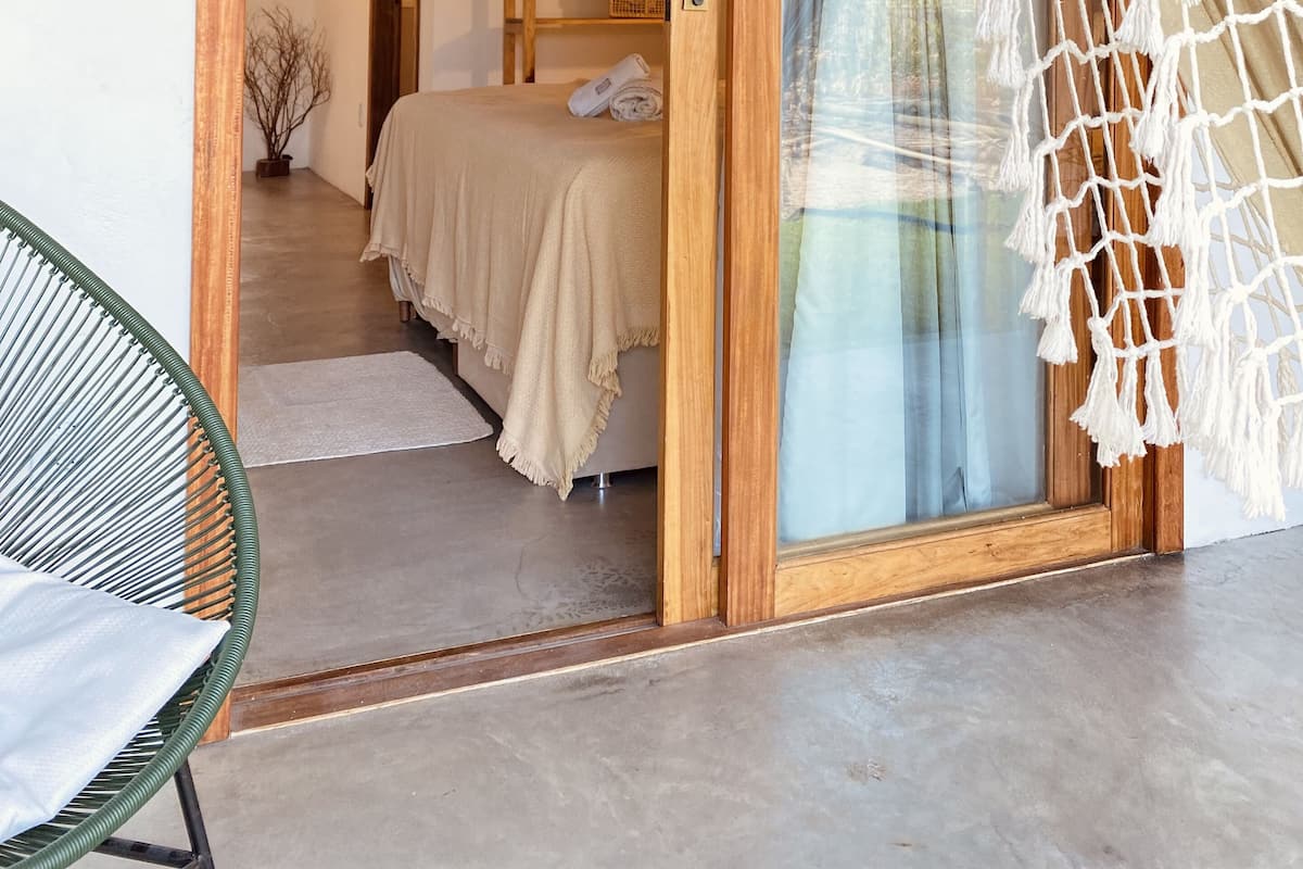Ein Zimmer mit einem Bett, einer Hängematte und einem Blumentopf.