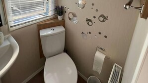 Un bagno piccolo con il water, lavandino e finestra con persiane.