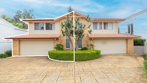 A two-story house with a garage, a driveway, and a well-maintained lawn.