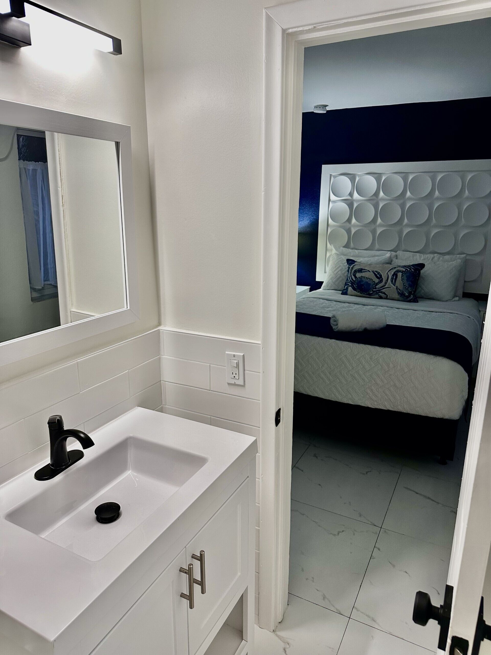 A modern bathroom with a white sink, mirror, and tiled walls.