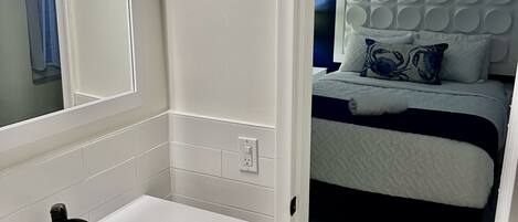 A modern bathroom with a white sink, mirror, and tiled walls.