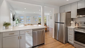 A modern kitchen with stainless steel appliances, white cabinetry, and a large island.