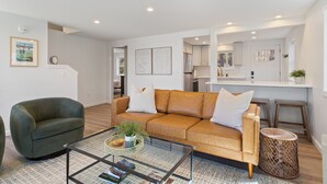 A modern living room with a leather sofa, a glass coffee table, and a green armchair.