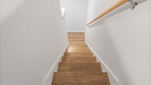 A wooden staircase with white walls and a light fixture.