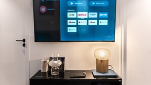 A flat-screen TV mounted on a wall displaying a digital interface with various application icons. - Hedonist House - Design Architect Flat - 15min. from Paris center (Gentilly)