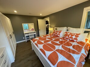 A bedroom with a bed, a desk, and a mirror.