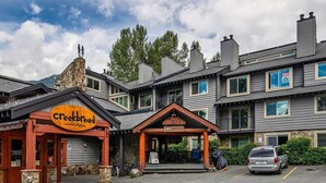 A lodge with a stone facade, a sign for Creekbreed wood-fired pizza, and a Whistler Creek Lodge sign.