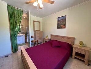 Cozy retreat with a large bed, wooden nightstand, and dresser, plus a convenient chair and shower.
