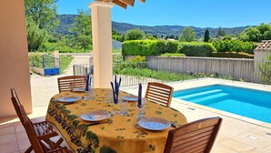 Une table à manger installée à l’extérieur, avec une piscine en arrière-plan.