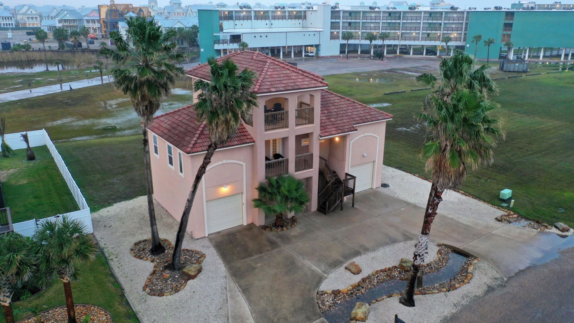 Ein mehrst öckiges Hotel mit rotem Ziegeldach, überdachter Terrasse und Palmen.