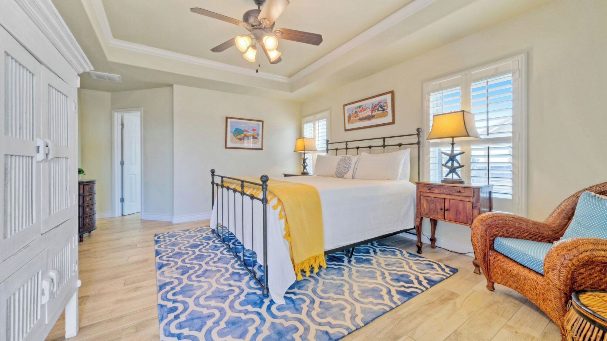 A bedroom with a bed, a chair, a nightstand, a ceiling fan, and a window with blinds.