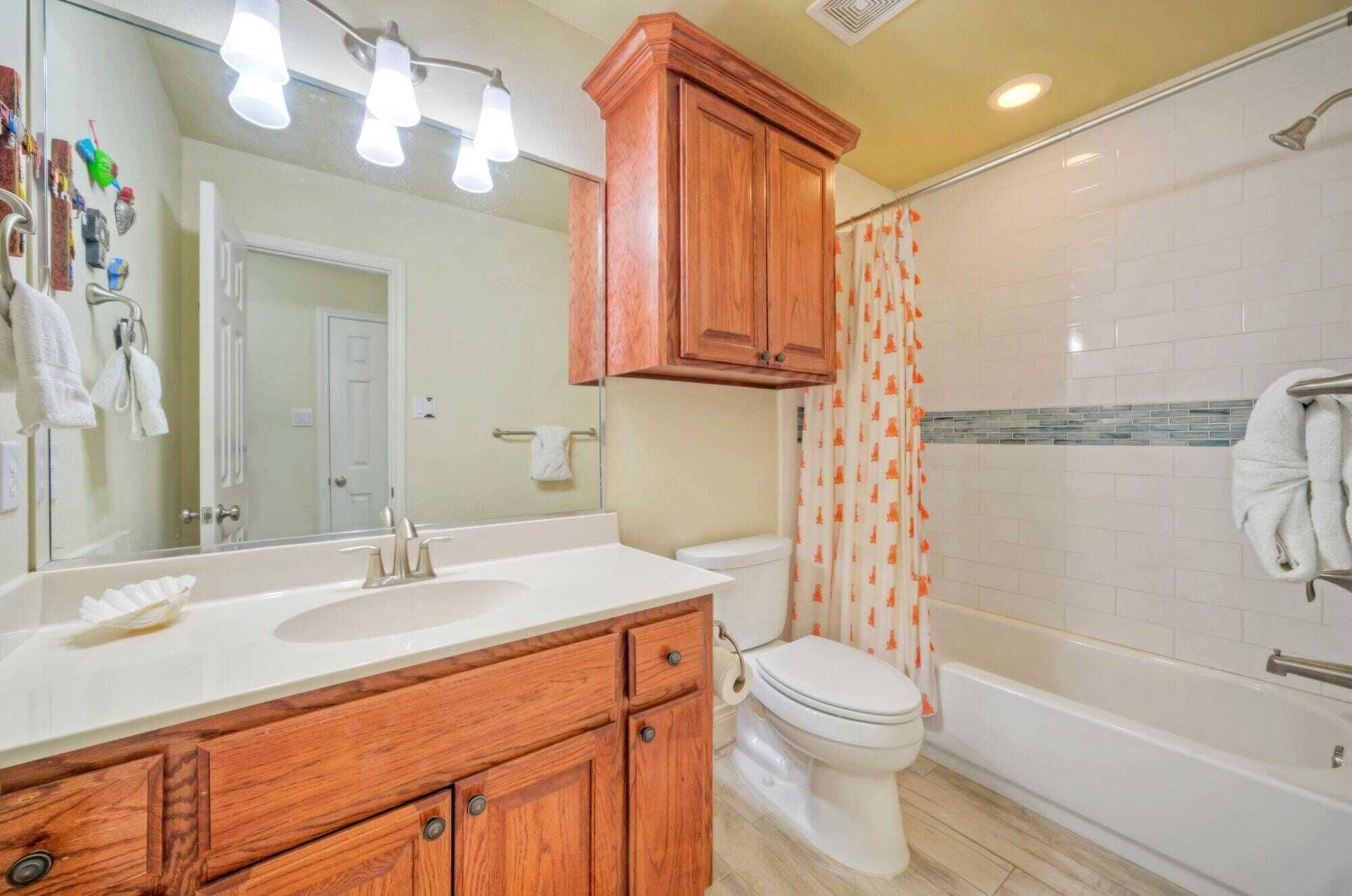 A bathroom with a wooden vanity, a toilet, and a bathtub.