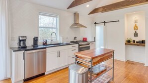 A modern kitchen with stainless steel appliances, a wooden countertop, and a hanging pot rack.